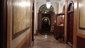 A hallway with a polished marble floor, wooden paneling, and a large arched doorway at the end.