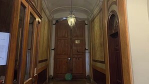 A hallway with wooden doors, a hanging lantern, and a green object on the floor.