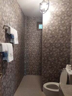 A bathroom with a shower, toilet, and towel rack. - Tung Na Pa Suan Farmstay (Doem Bang Nang Buat)