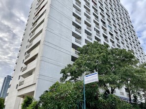 A tall, modern building with multiple balconies and a sign indicating it is a condominium. - Paradise Condominium by PSR (Pattaya)