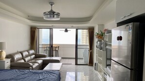 Una habitación de hotel moderna con cama, sofá, mesa de comedor y balcón con vistas a la ciudad.