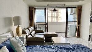 Habitación de hotel con cama, sofá, una mesita, lámpara y vista a un edificio a través del ventanal.