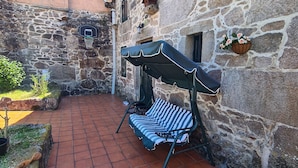 A stone building with a tiled patio, a basketball hoop, and a striped outdoor sofa. - ¡A 10 Minutos de Santiago de Compostela! Casa Ideal Para Familias (la esclavitud,Padron)