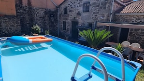 A swimming pool with a ladder, surrounded by stone buildings and a clear blue sky. - ¡A 10 Minutos de Santiago de Compostela! Casa Ideal Para Familias (la esclavitud,Padron)