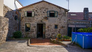 A stone building with a tiled entrance, a small porch, and a blue fence. - ¡A 10 Minutos de Santiago de Compostela! Casa Ideal Para Familias (la esclavitud,Padron)