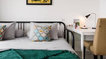 A neatly arranged bedroom with a bed, a desk, and a chair.