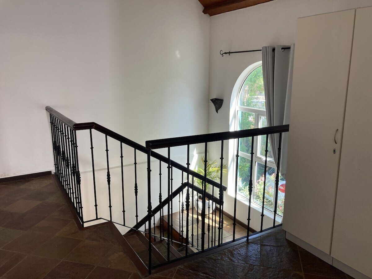 Una escalera con barandillas negras que da a un rellano.