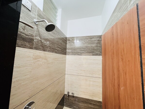 A bathroom with a shower, tiled walls, and a wooden door.