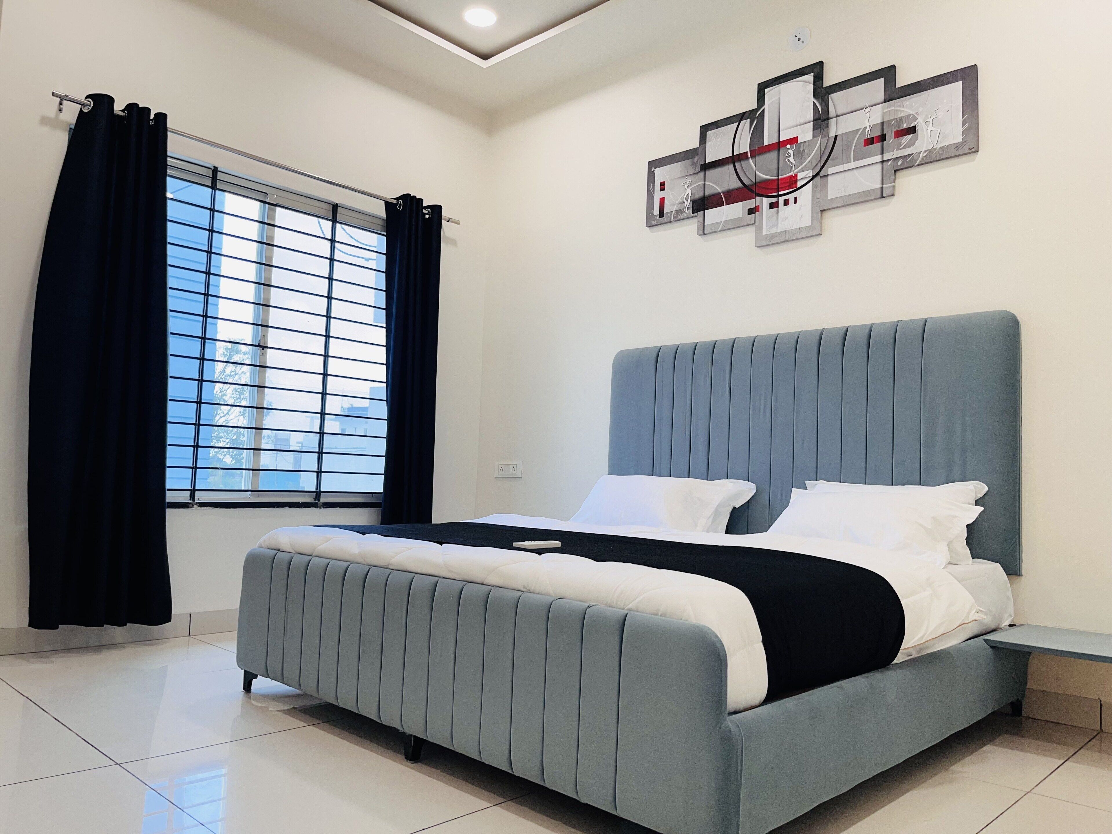 Un dormitorio moderno con una cama grande, una ventana con cortinas y una obra de arte en la pared.
