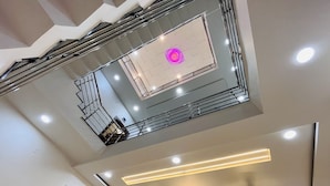 A multi-level interior with a central open space, staircases, and modern lighting fixtures. - Home Escape Luxe (Ujjain)