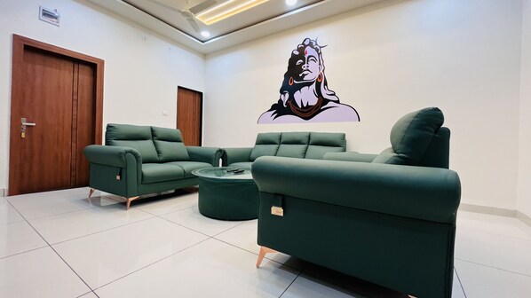 A modern living room with a green sofa set, a coffee table, and a wall-mounted artwork. - Home Escape Luxe (Ujjain)