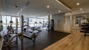A gym with cardio machines, weightlifting equipment, and a mirror wall. - Two Bed Room 5 minutes to Burj Khalifa & Dubai Mall-DAMAC REVA Residence 2705 (Dubai)