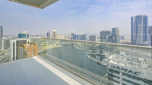 A high-rise building with a glass balcony overlooking a marina and cityscape. - Two Bed Room 5 minutes to Burj Khalifa & Dubai Mall-DAMAC REVA Residence 2705 (Dubai)