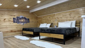 Un dormitorio con dos camas, paredes de madera e iluminación empotrada en el techo.
