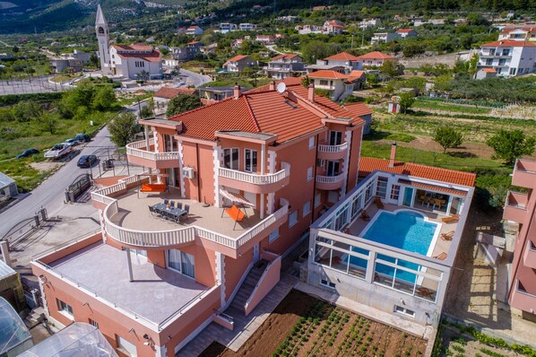 A multi-story residential building with a rooftop terrace, a swimming pool, and a church in the background.