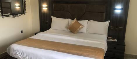A neatly made bed with white and brown linens, a dark headboard, and bedside tables with lamps.