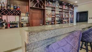 A bar area with shelves of bottles and a counter. - Roban Hotels Limited (Enugu)