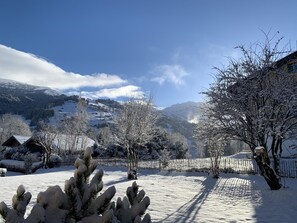 Un paysage enneigé, avec un ciel dégagé, une cour entourée d’une clôture et une montagne en arrière-plan.