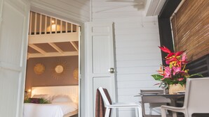 A room with a bed, a dining table with chairs, and a door leading to another room. - Ilet du Lagon (Saint-Paul)