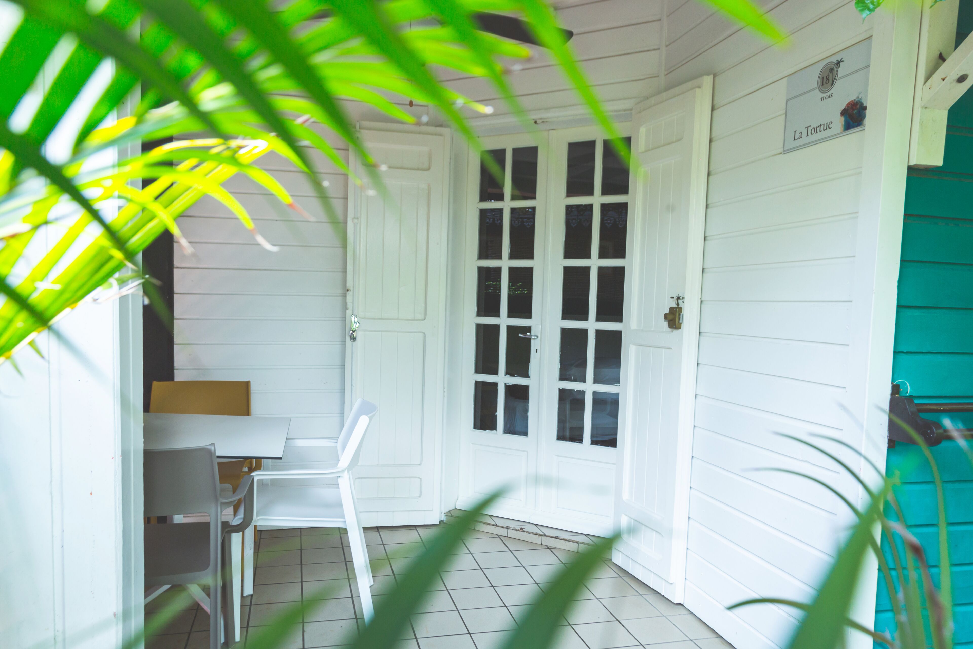A room with white walls, a tiled floor, a white door, and a green wall.