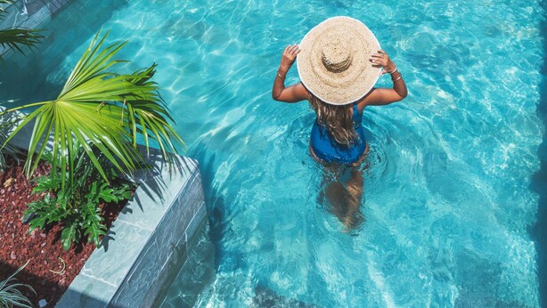 A swimming pool with clear blue water, surrounded by a low stone wall and lush greenery. - Ilet du Lagon (Saint-Paul)