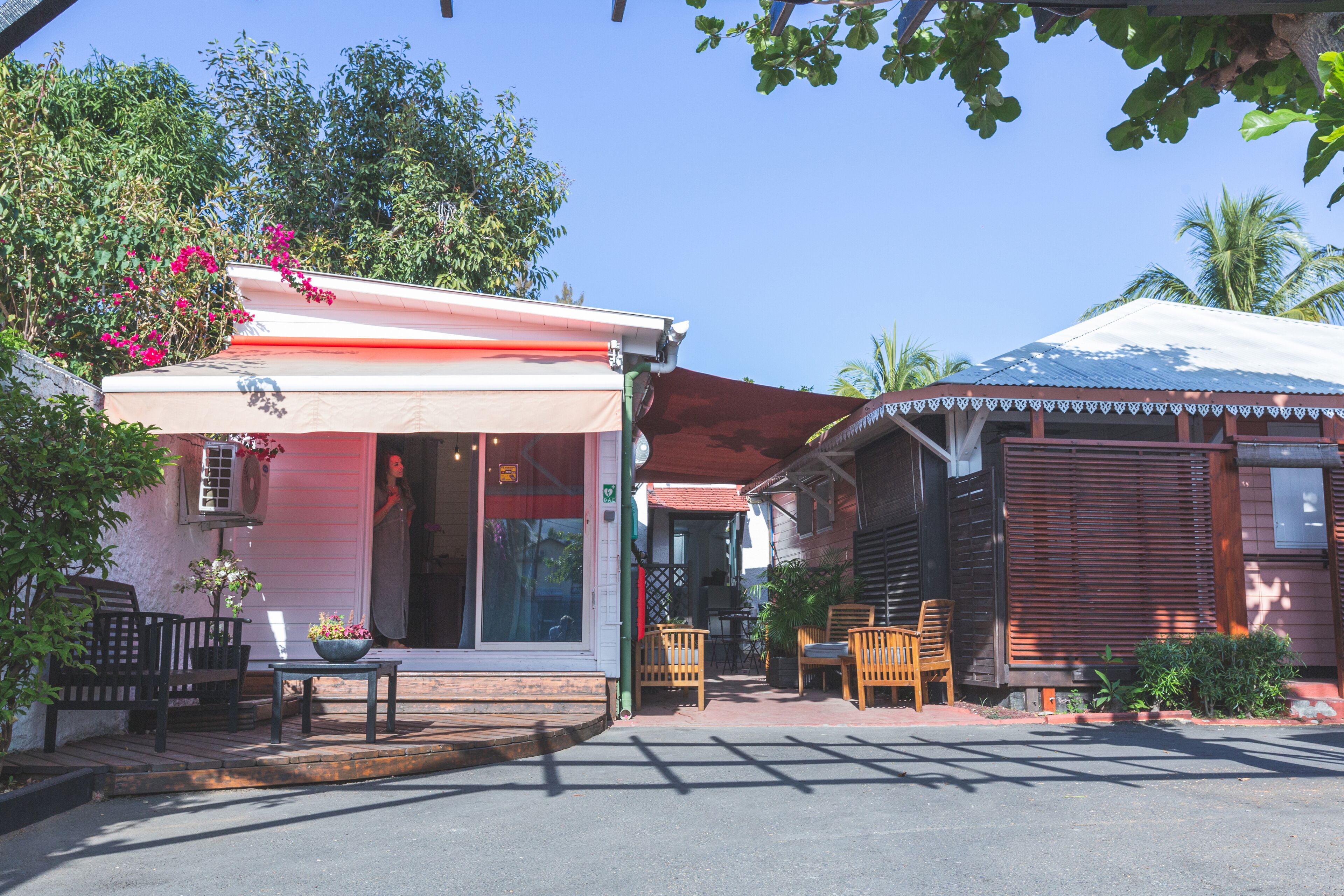 A building with a porch, outdoor seating, and a red awning.