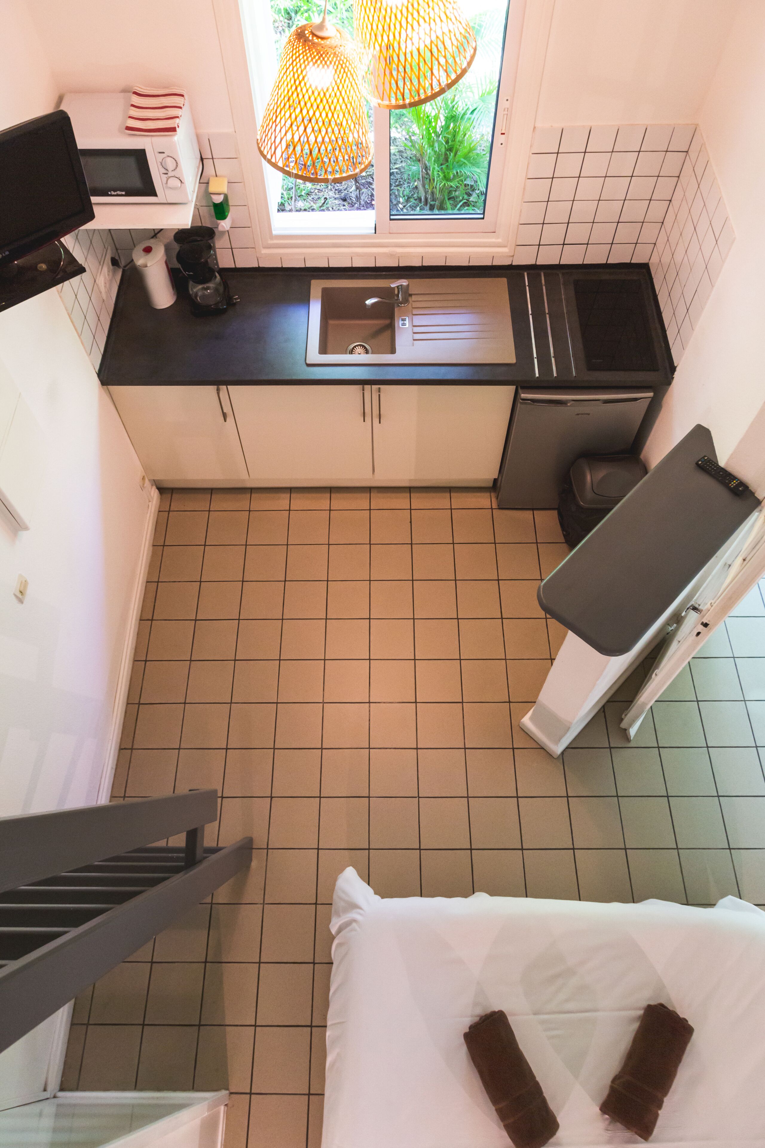 A compact kitchen with a microwave, sink, and window with a view of greenery.