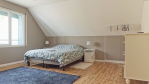 Un dormitorio con cama, mesitas de noche, cómoda, ventana y ventilador de techo.