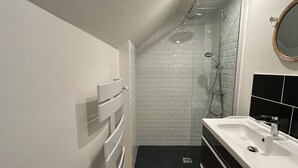 Un baño moderno con ducha, lavamanos y espejo.