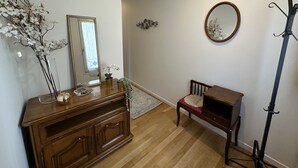 Una habitación con tocador de madera, una silla, un espejo y una lámpara de pie.