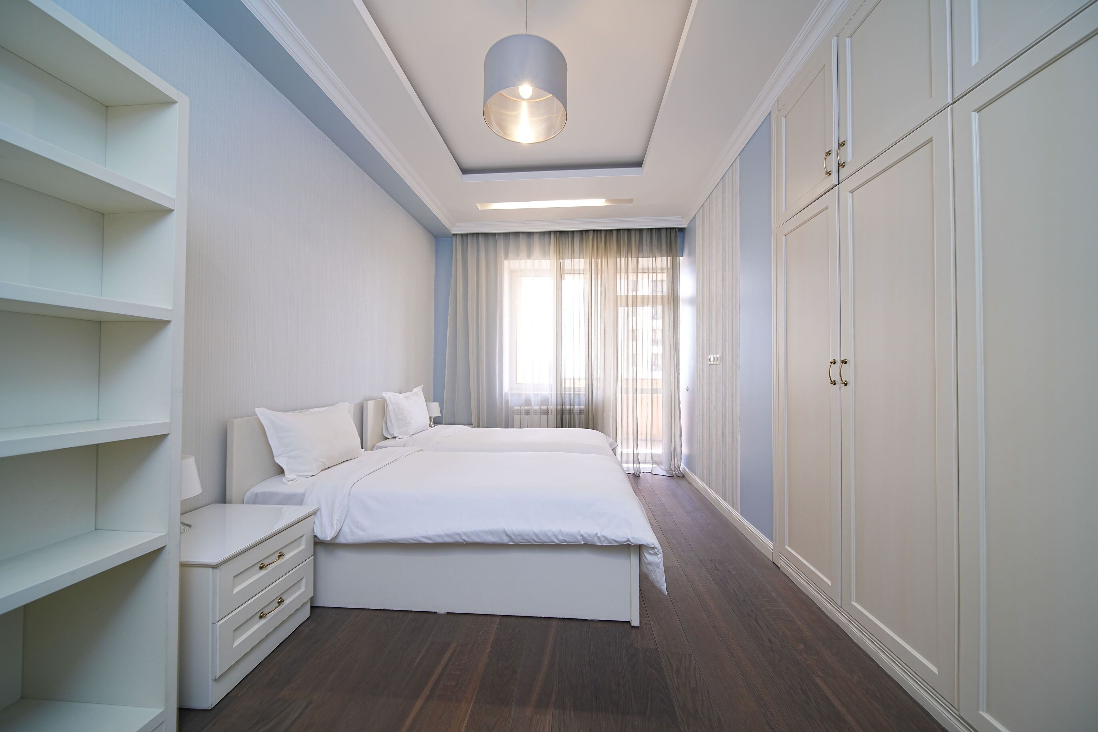 Une chambre à coucher avec un grand lit, une table de chevet, une armoire et un luminaire au plafond.