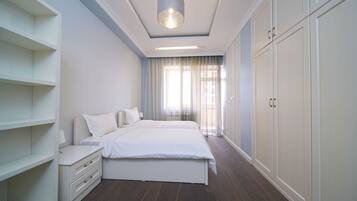 Une chambre à coucher avec un grand lit, une table de chevet, une armoire et un luminaire au plafond.