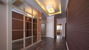 A hallway with a sliding door, a door with a mirror, and a light fixture on the ceiling.