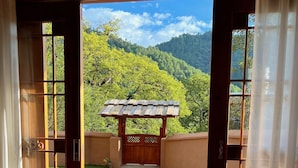 A room with a view of a lush green landscape through a wooden door. - Shujiawuxiangluoguqingtubuminsu (Nujiang Lisu)