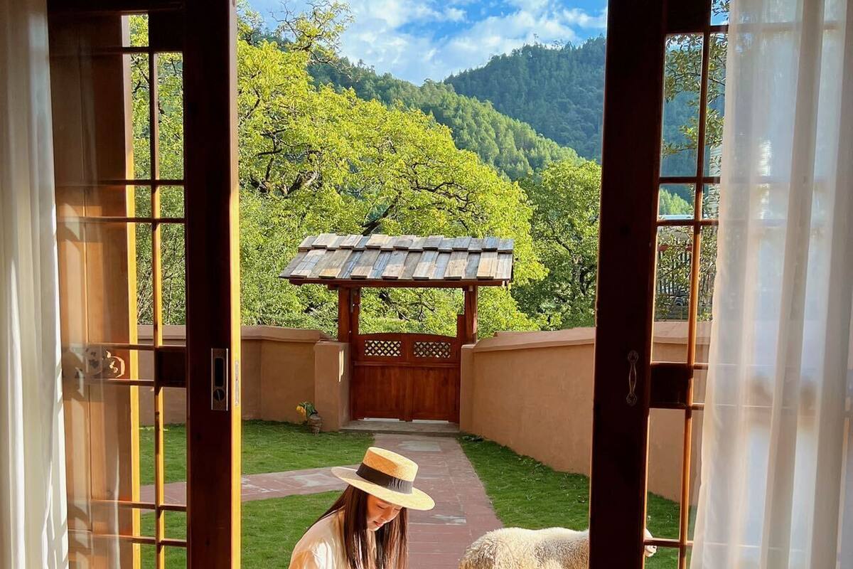 A room with a view of a lush green landscape through a wooden door.