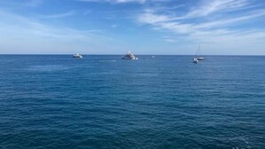 A calm sea with several boats, including a yacht and a sailboat, under a clear sky. - Above the rooftops of Antibes (Antibes)