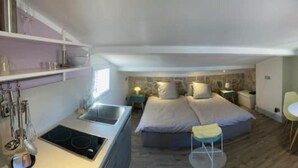 A compact room with a kitchenette, a bed, a small dining table, and a chair. - Above the rooftops of Antibes (Antibes)