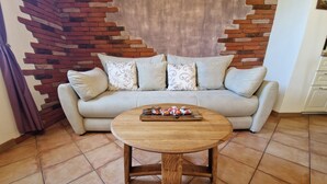 A living room with a sofa, a wooden coffee table, and a brick accent wall. - Apartment  (Koper)
