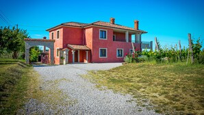 A two-story house with a red facade, a stone archway entrance, and a gravel driveway. - Apartment  (Koper)