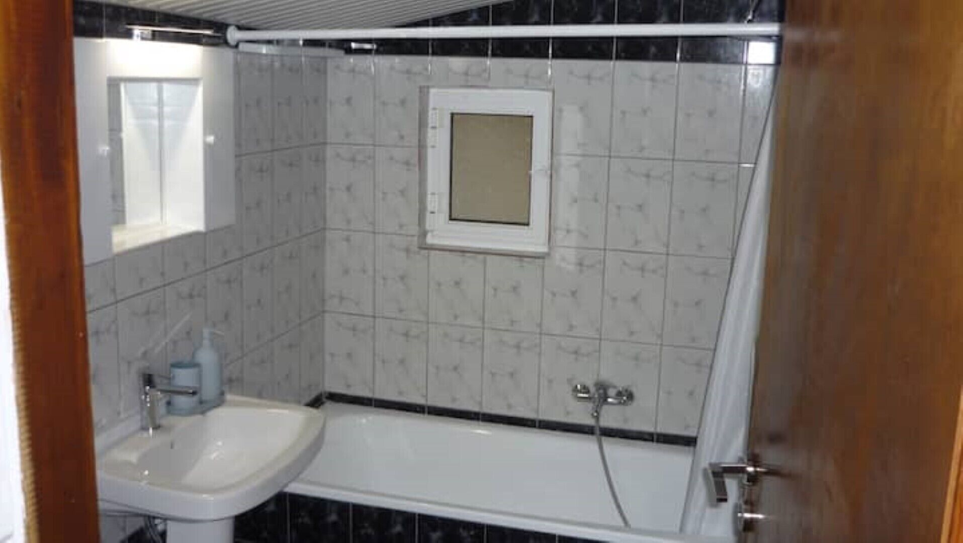 Un baño con un lavamanos blanco, una bañera y un espejo.