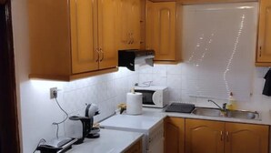 A compact kitchen with wooden cabinets, a microwave, a toaster, and a sink. - Nakou's House-Το σπίτι του Νάκου (Liopraso)