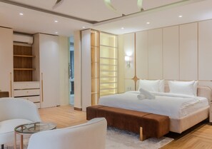 A modern bedroom with a large bed, a seating area with a glass table, and a wardrobe with a mirror. - Lakowe Lakes Hotel Golf and Country Estate by NEWMARK (Lekki)