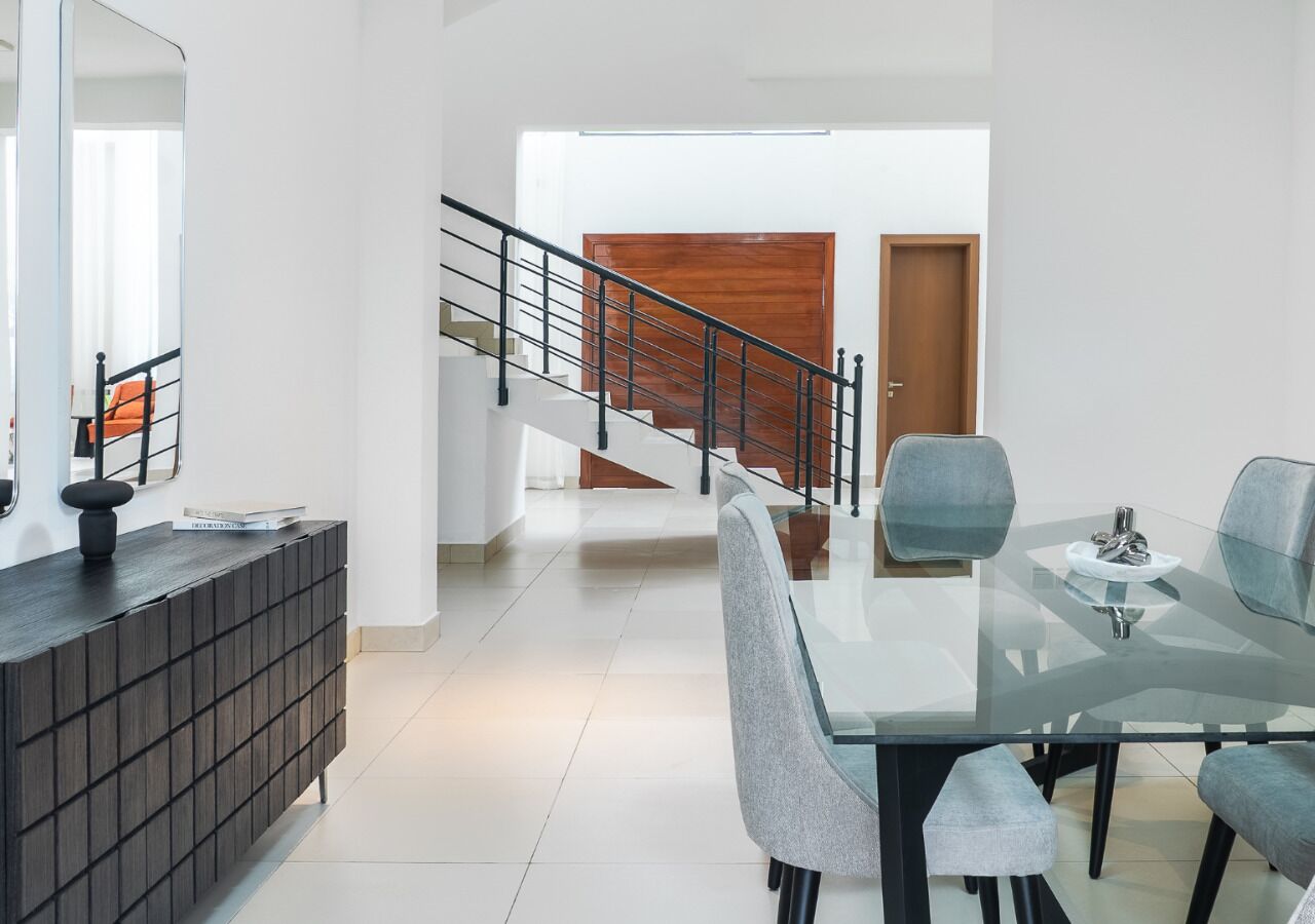 Un interior moderno con comedor, una escalera y vista a otra habitación.