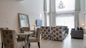 A living room with a round dining table, floral-patterned sofas, and a grey armchair. - Lakowe Lakes Hotel Golf and Country Estate by NEWMARK (Lekki)