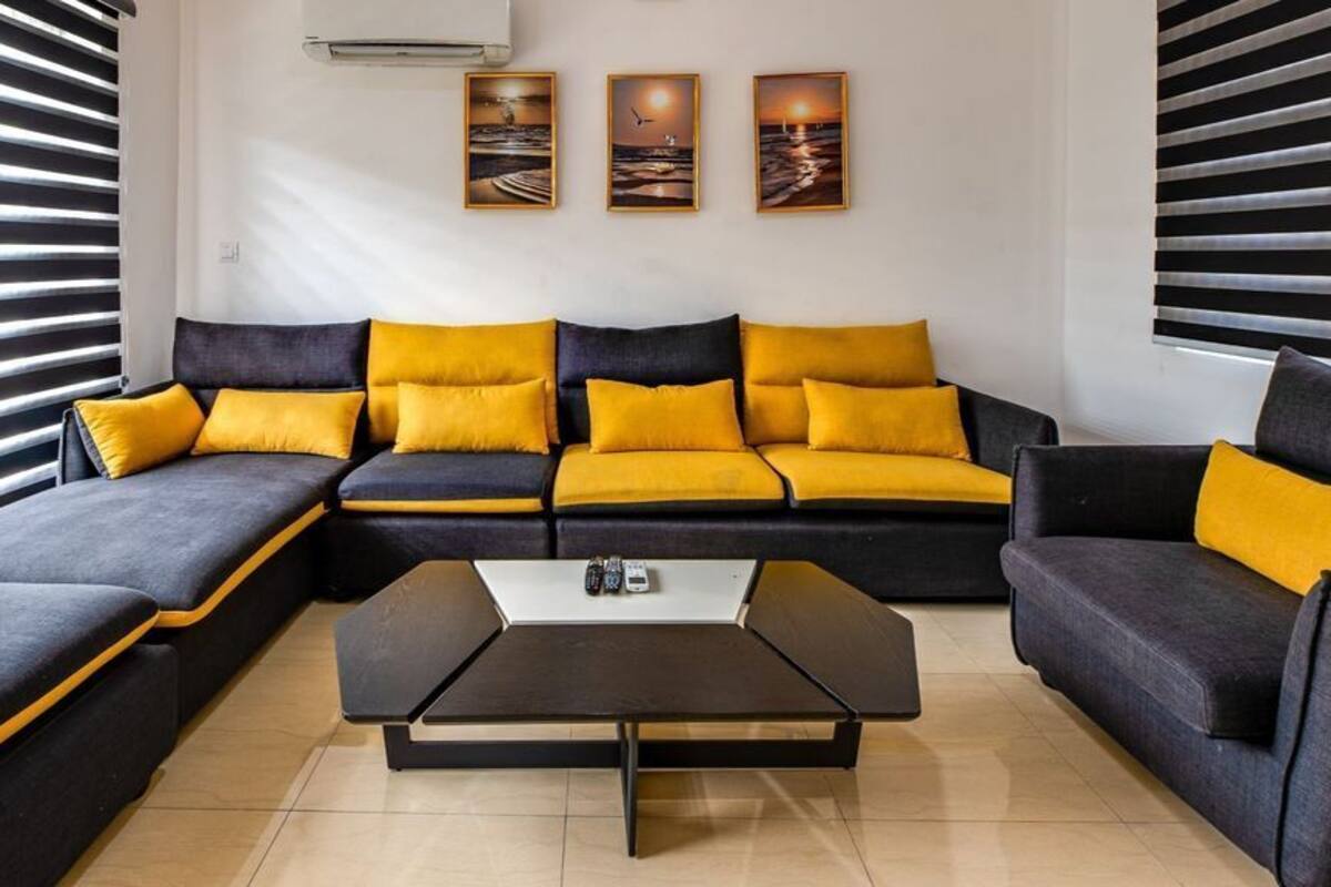 Una sala moderna con un sofá seccional, una mesa de centro y tres cuadros en la pared.