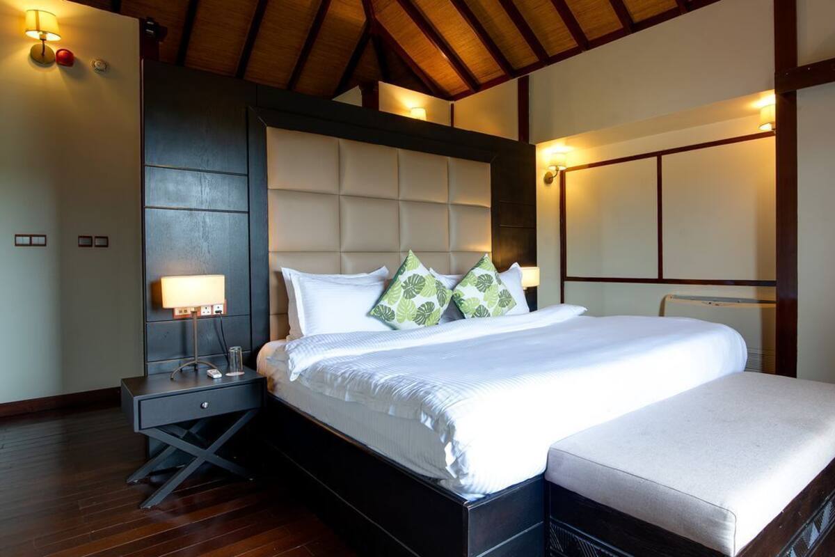 Un dormitorio moderno con una cama grande, una mesita de noche y una lámpara fijada a la pared.