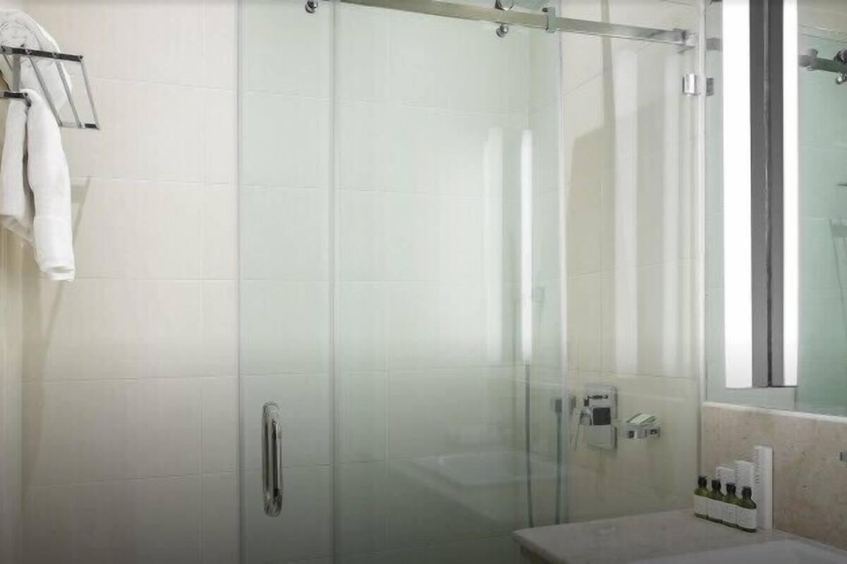 Un baño moderno con cabina de ducha de vidrio, tocador con espejo y perchero para toallas.