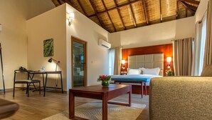 A hotel room with a bed, a sofa, a desk, and a chair. There is a window with curtains, a door, and an air conditioning unit on the wall. - Lakowe Lakes Hotel Golf and Country Estate by NEWMARK (Lekki)