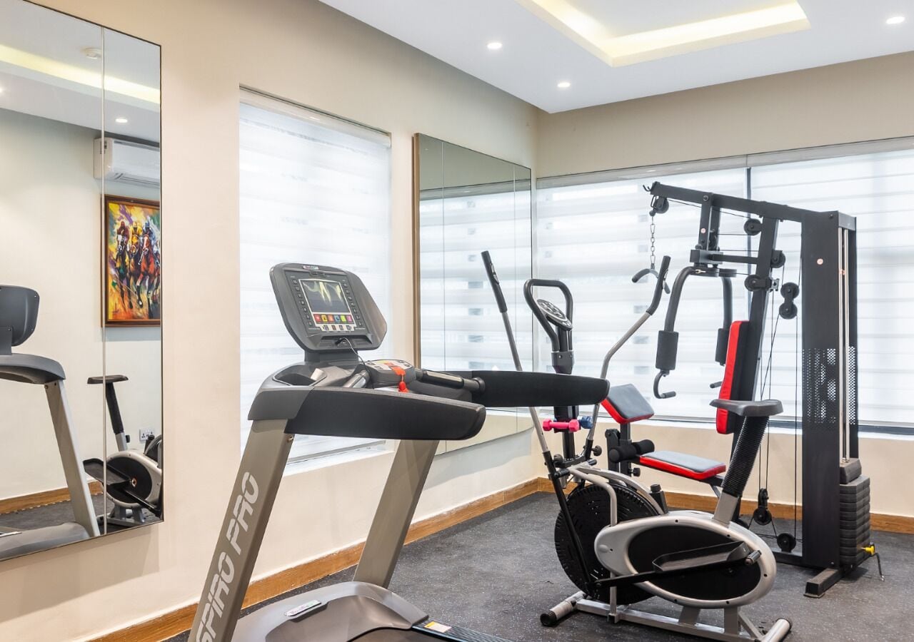 A gym with cardio equipment, weight machines, and a mirror.