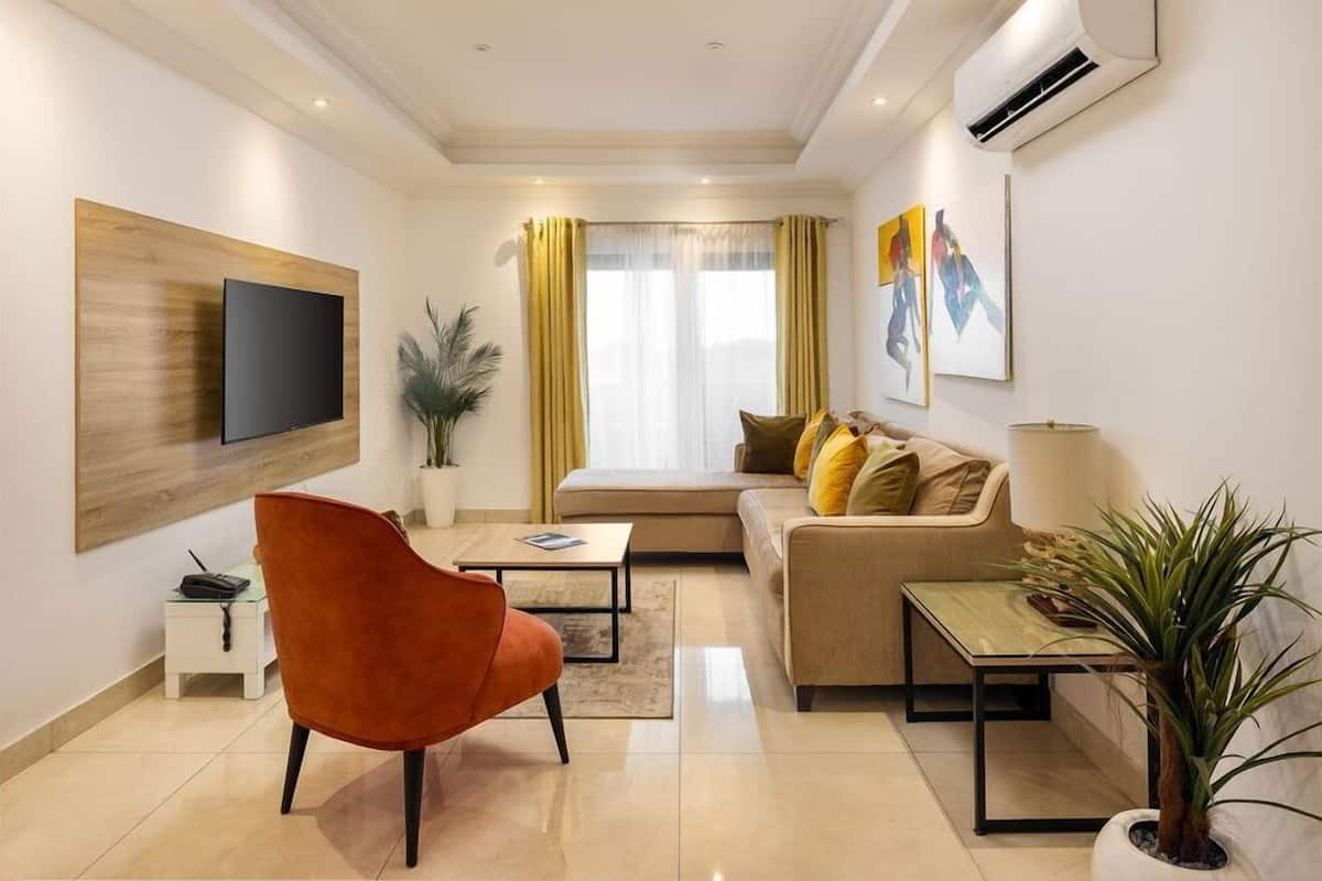 Una sala de estar moderna con sofá, sillón, televisor y obras de arte.